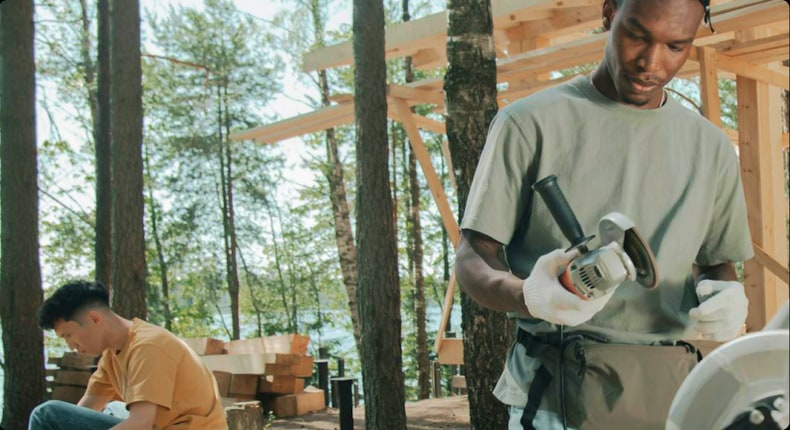 A builder holding a power tool on a timber-frame construction site